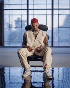 a man with red hair sitting in a chair looking at his cell phone while wearing all white