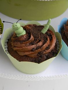 two cupcakes with chocolate frosting and a caterpillar sitting on top