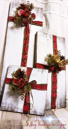 two wrapped christmas presents sitting on top of a white wooden board with red and green ribbon