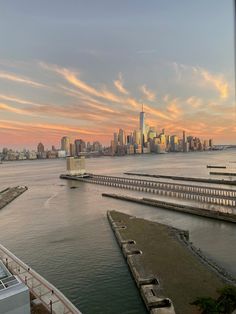 the city skyline is seen from across the water at sunset, with boats in the harbor