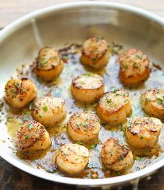 a pan filled with cooked scallops on top of a wooden table