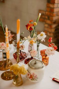 a table topped with vases filled with flowers and candles