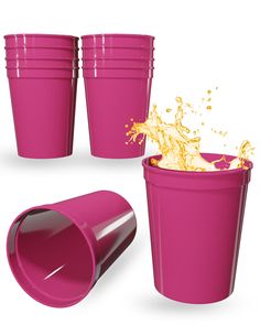 pink plastic cups with splashing orange liquid on the top and bottom, set against a white background