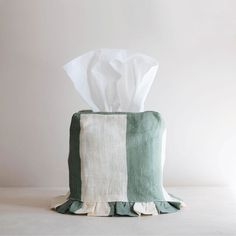 a green and white striped tissue holder on a table