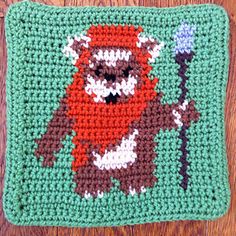 a crocheted square with an image of a red panda holding a blue flower