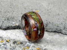 a wooden ring with plants growing out of it sitting on the ground next to some rocks