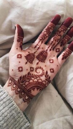 a person's hand covered in henna on top of a white bed sheet