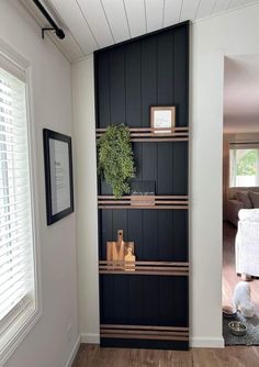 a black bookcase in the corner of a room with wood floors and white walls