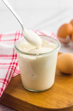 a spoon with yogurt in it on a cutting board next to some eggs