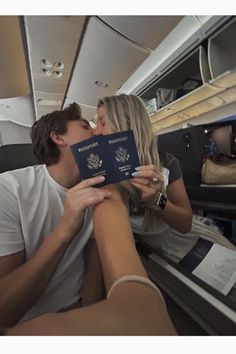 a man kissing a woman on the cheek while she is holding a passport in her lap