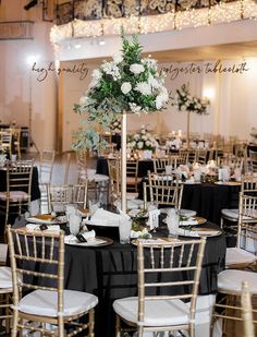 the tables are set up with black linens and white flowers in tall vases