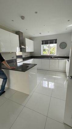 a man leaning on a counter in a kitchen with white cabinets and black counter tops