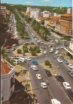 an aerial view of a city street with cars driving on the road and palm trees in the background