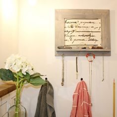 there is a vase with flowers next to a coat rack and some keys hanging on the wall