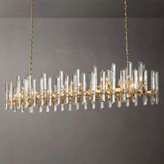 a chandelier hanging from a gold chain with clear glass tubes in the middle