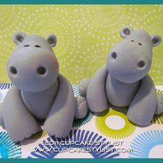 two gray hippos sitting next to each other on top of a tablecloth