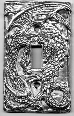 a light switch cover with an intricate dragon design on the front and back covers in silver