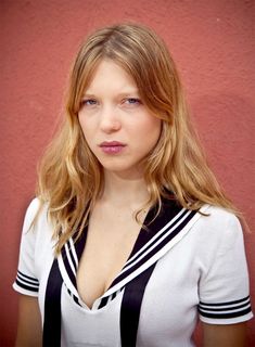 a woman with long blonde hair wearing a white shirt and black suspenders posing for a photo