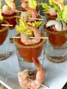 small glasses filled with shrimp and garnish on a white plate