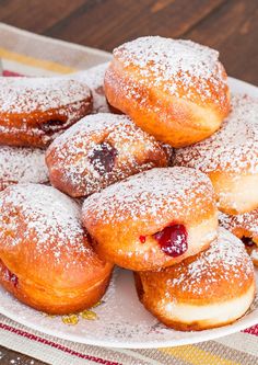 a pile of powdered sugar covered donuts on a plate