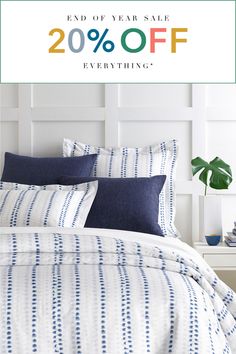 a bed with blue and white sheets, pillows and blankets on it that says end of year sale 20 % off everything