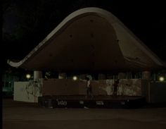 a man standing in front of a large structure with lights on it's sides