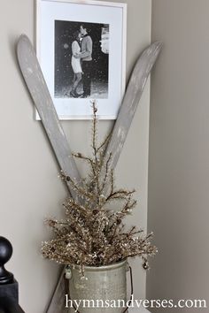 a vase filled with flowers and two skis on top of a table next to a framed photo