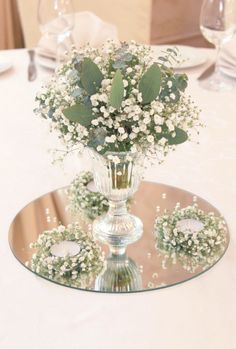 a glass vase filled with white flowers on top of a table