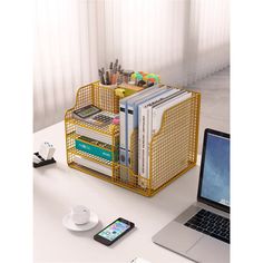 a laptop computer sitting on top of a desk next to a yellow basket filled with books