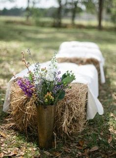 there is a vase with flowers in it on the ground next to hay bales