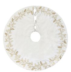 a white and gold tree skirt with leaves on the bottom, hanging from a metal hook