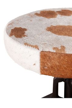 a brown and white spotted stool with black metal legs on an isolated white background for use as a side table