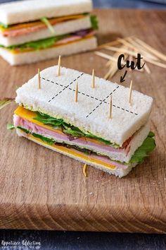 a cut in half sandwich sitting on top of a cutting board with toothpicks sticking out of it