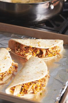 three burritos sitting on top of a baking sheet