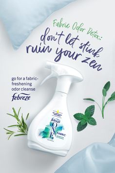 a bottle of fabric cleaner sitting on top of a bed next to green leaves and blue sheets