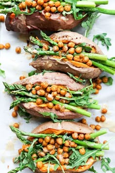 some food that is laying on top of a white plate with asparagus and chickpeas