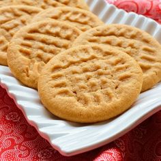 two cookies sitting on top of a white plate next to a red and pink table cloth