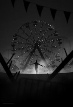 the silhouette of a person standing in front of a ferris wheel with lights on it