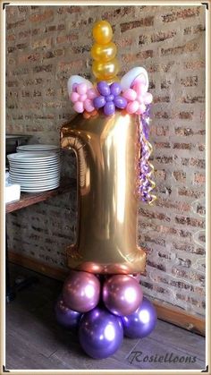 a large balloon in the shape of a beer mug with balloons attached to it, sitting on top of some plates