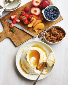 a plate with fruit and ice cream on it next to bowls of berries, peaches, blueberries and other foodstuffs