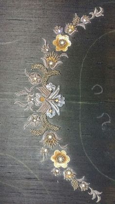 an intricately designed piece of cloth with flowers and pearls on the edge, sitting on a wooden surface