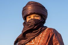 a woman wearing a black head scarf and a brown shawl on top of her head