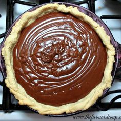 a chocolate pie sitting on top of a stove next to an empty pan with sauce in it