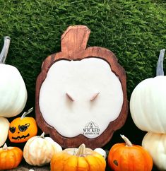 pumpkins and gourds are arranged in front of a carved wooden sign with the face of an owl on it