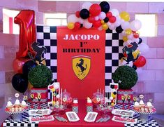 a red table topped with lots of balloons next to a black and white checkered table cloth