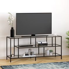 a flat screen tv sitting on top of a metal stand next to a potted plant