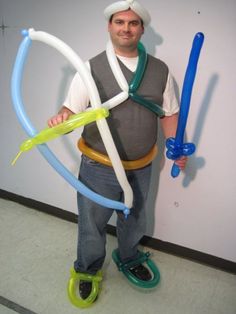 a man standing in front of a white wall holding two large blue and yellow balloons