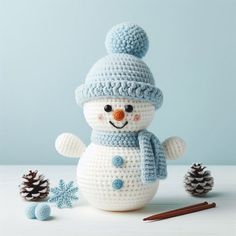 a crocheted snowman is next to pine cones and two small knitted balls