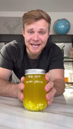 a man sitting at a table with a jar of food in front of him