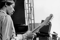 a man holding a guitar in his right hand and looking at the strings on it